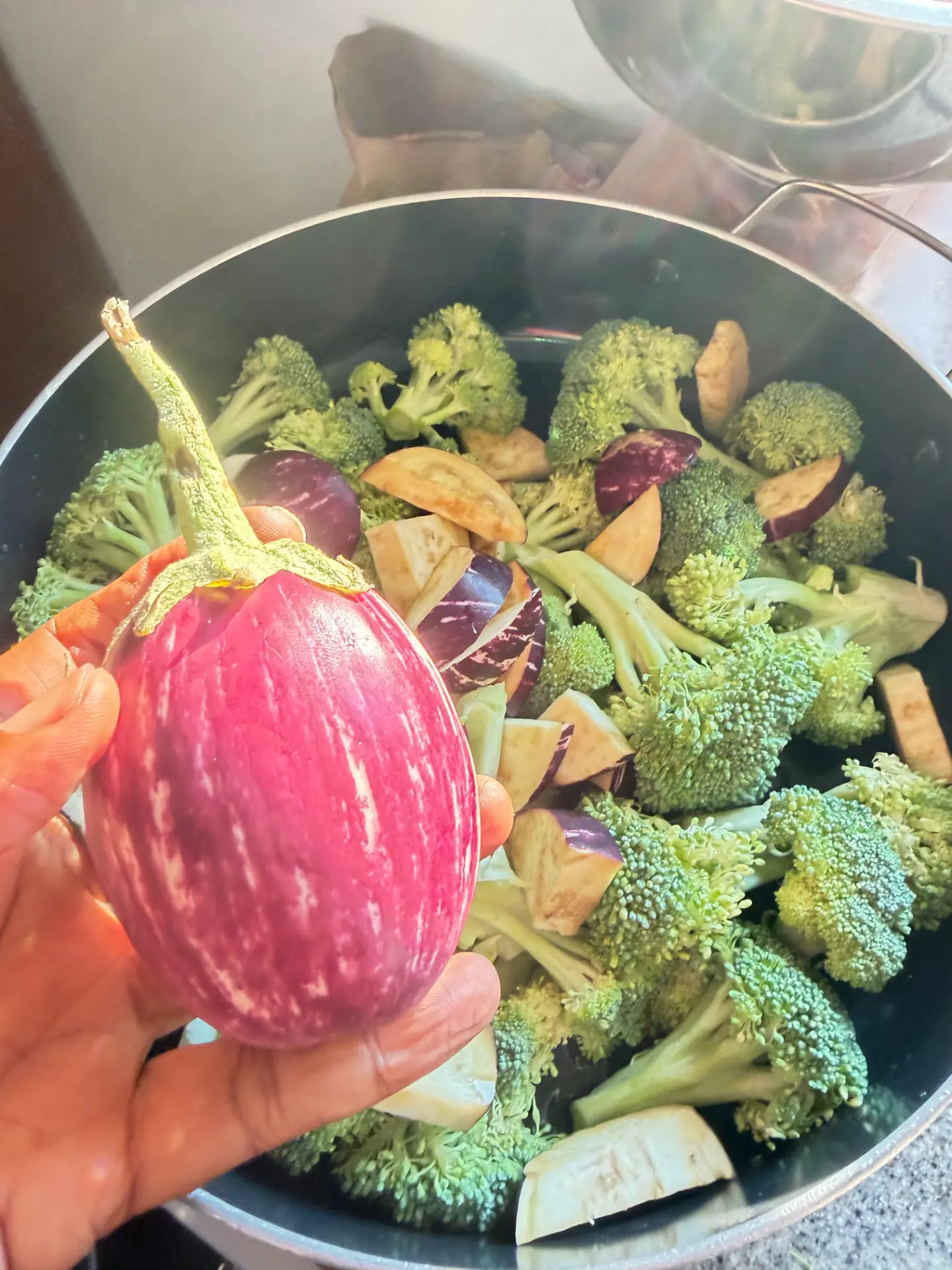 Fresh striped eggplant over broccoli in the pot
