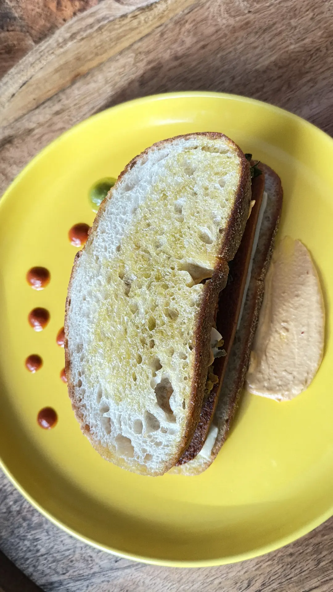 Sourdough sandwich plated on a yellow dish with sauces